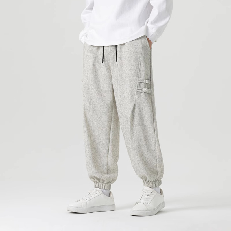 Black minimalist joggers with tailored drape and traditional Eastern knot accents on the thigh