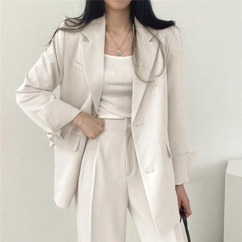Women's tailored suit set featuring long structured blazer and high-waisted trousers for polished elegance