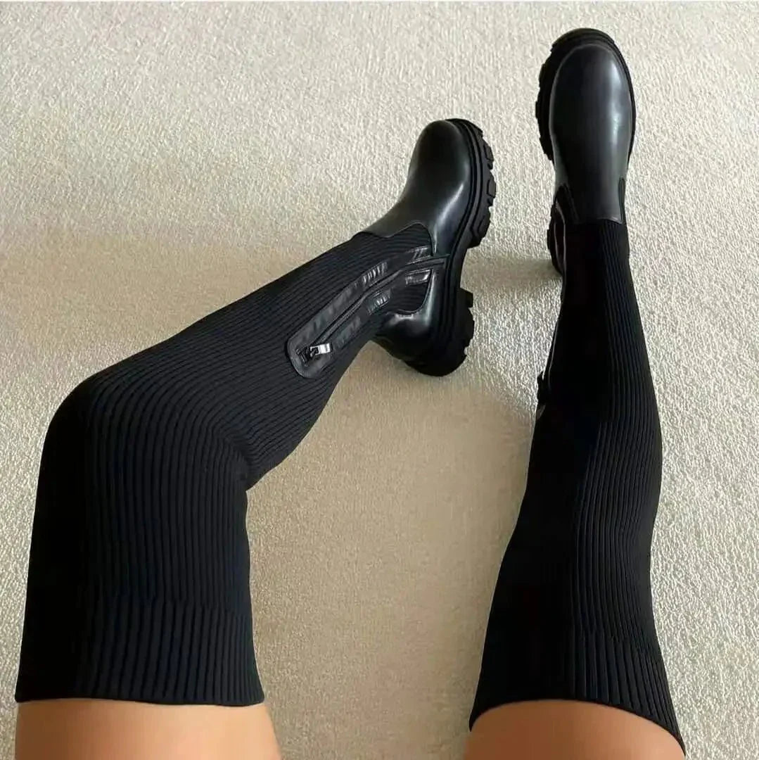 Black thigh-high sock boots with stretchy knit shaft, block heel, and sleek contemporary silhouette