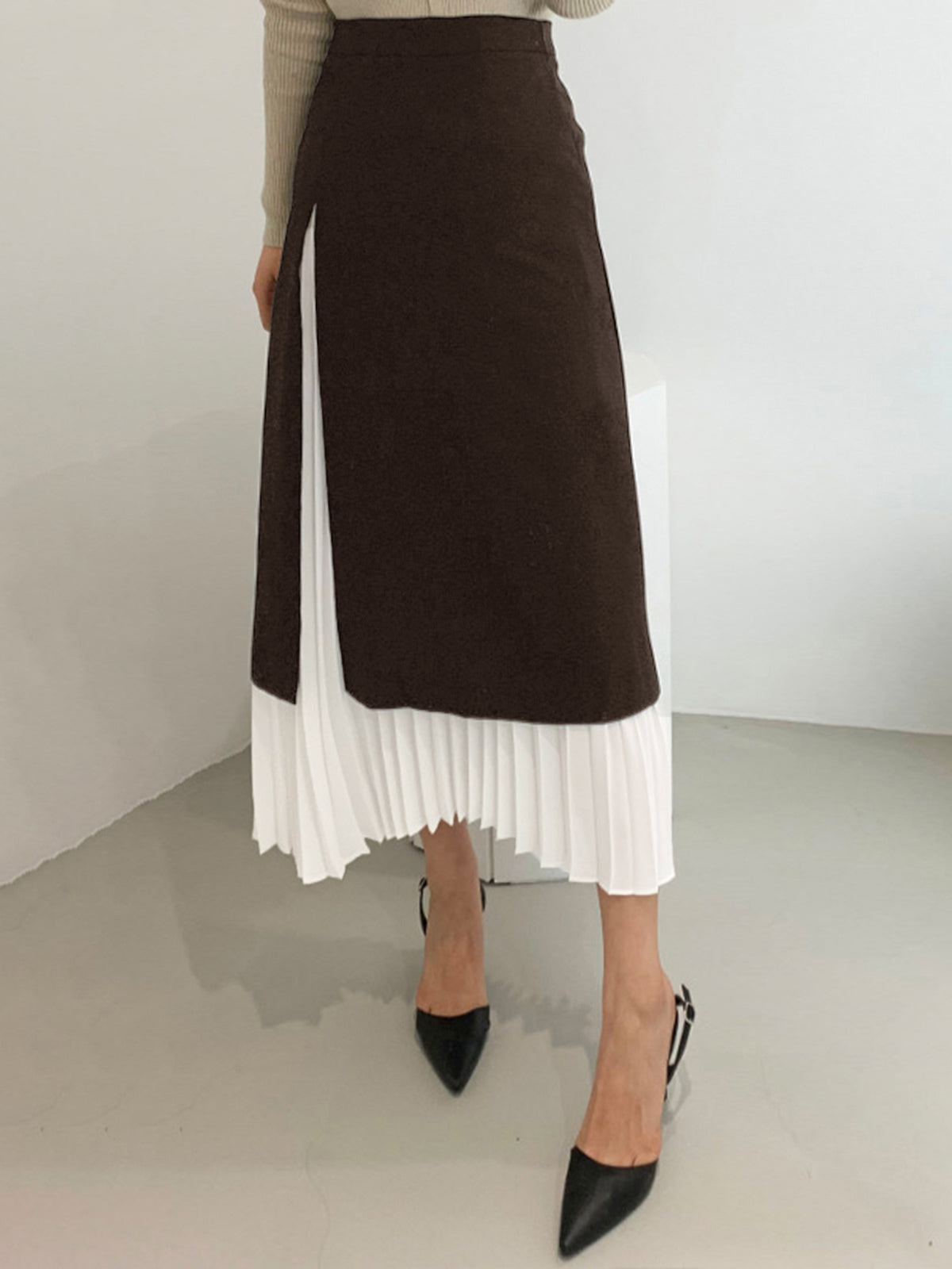 Black and white two-tone pleated midi skirt with flowing pleats and layered silhouette