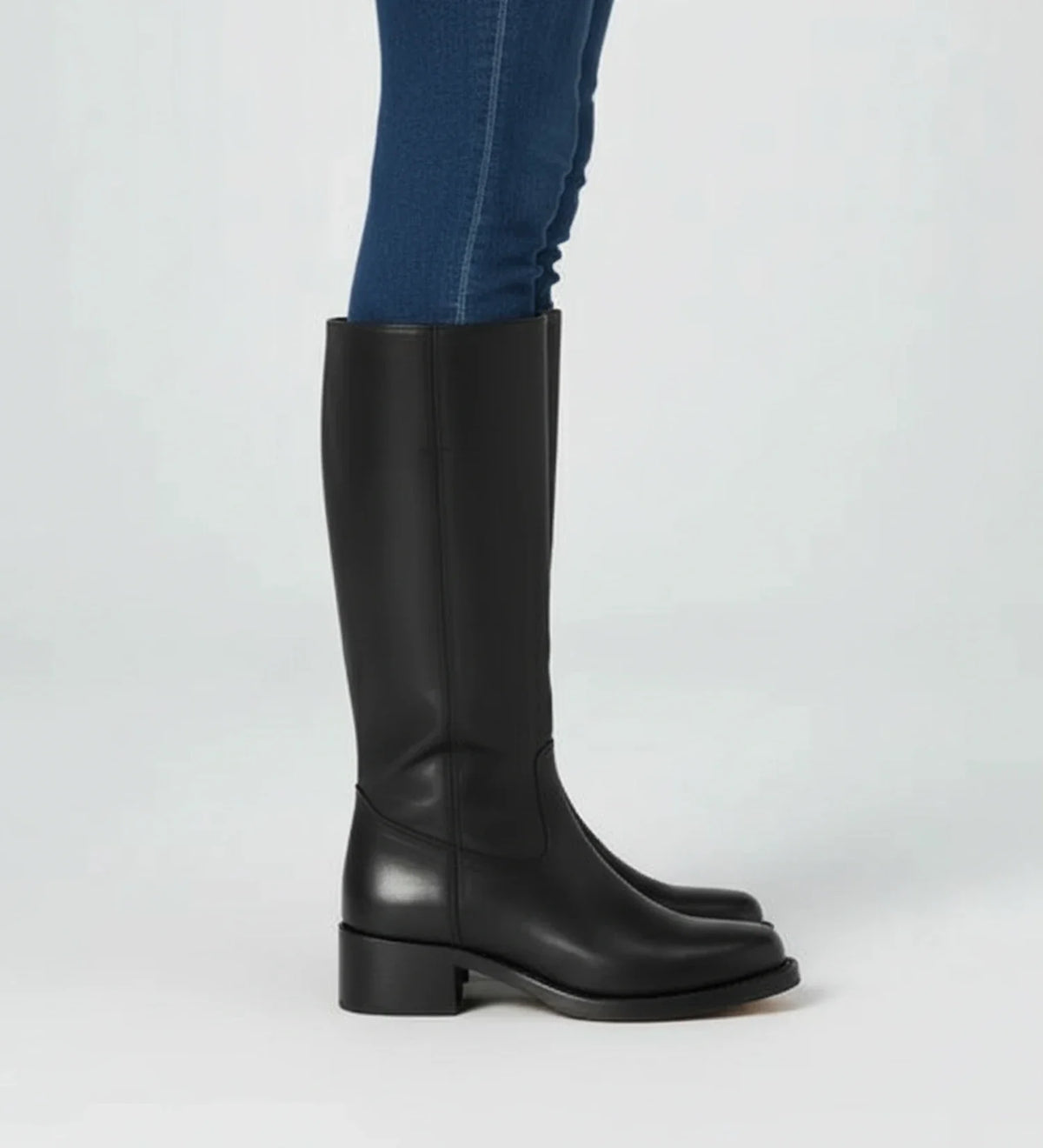 Women's black faux leather knee-high block heel boots with Western-inspired pull-on silhouette