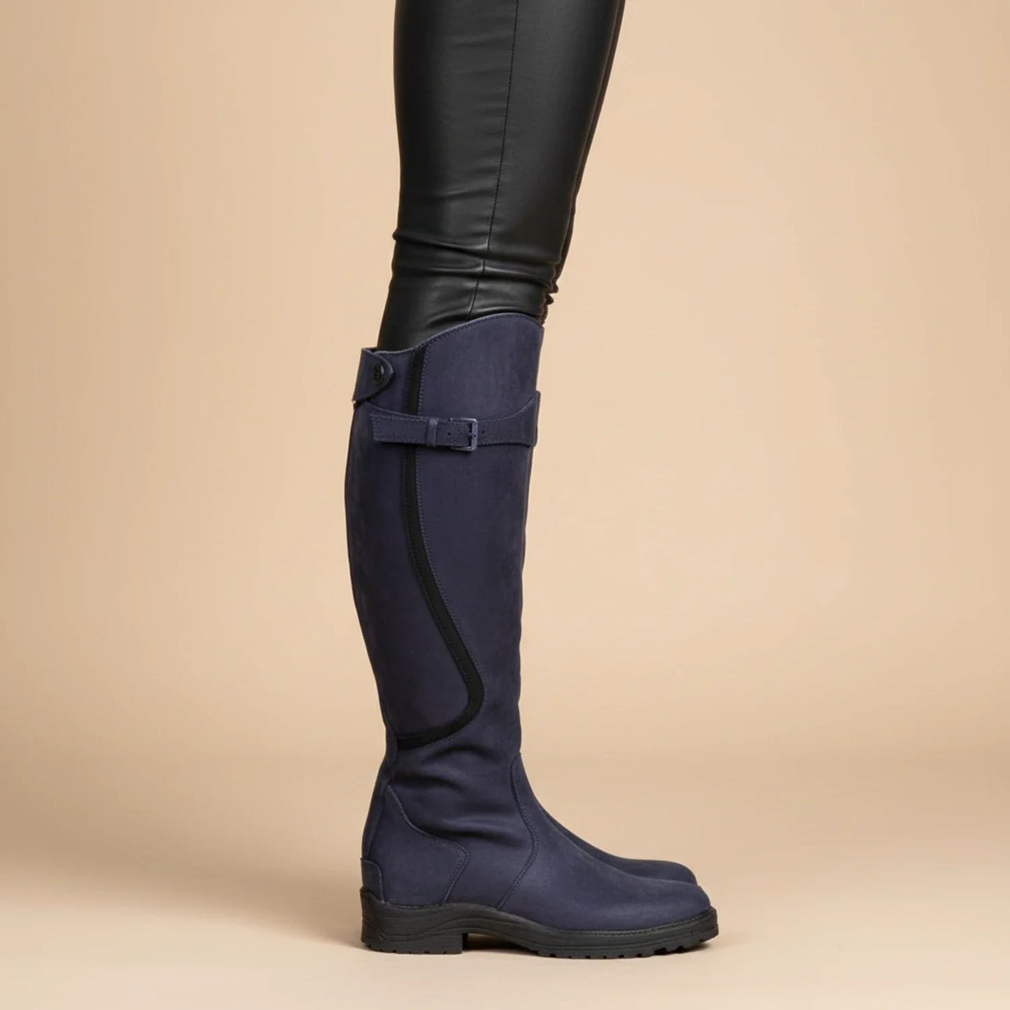 Women's brown leather knee-high riding boots with buckle detail and flat heel equestrian style
