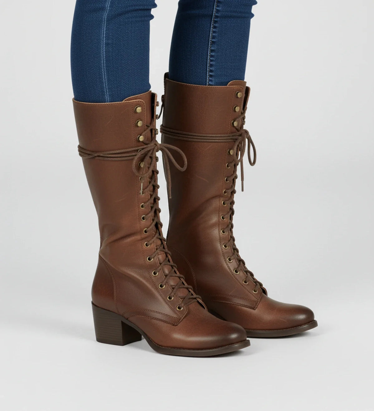 Women's black knee-high combat boots with block heel, lace-up front, grommet details, and back zipper