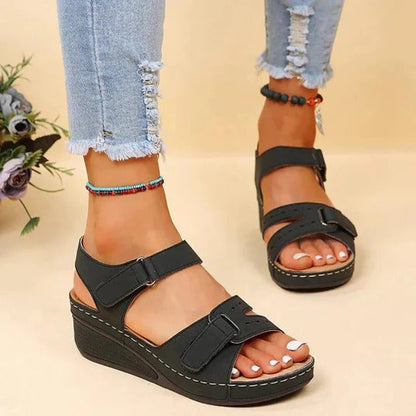 Women's flat walking sandals in neutral tone with adjustable twin buckle straps and open heel